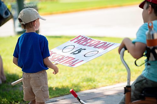 Mike Sudoma / Winnipeg Free Press
A young supporter of The Line, a group against the CoVid quarantine/restrictions, looks at a signs theyre holding as they rally along Broadway St with their parents and other supporters Saturday afternoon
July 24, 2020