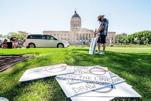 Mike Sudoma / Winnipeg Free Press
A supporter of The Line, a group against the CoVid quarantine/restrictions, as they look down at various picket signs used at the rally along Broadway St Saturday afternoon
July 24, 2020