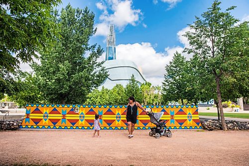 MIKAELA MACKENZIE / WINNIPEG FREE PRESS

Sue Tucker and her granddaughter, Penny Sinclair-Peters-Tucker (two), walk past a new mural, Wokpan Shina, by artist Kristin Flattery at The Forks in Winnipeg on Tuesday, July 28, 2020. The design is inspired by traditional beading, where the stitches represent diversity and resilience. Standup.
Winnipeg Free Press 2020.