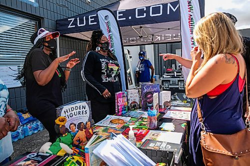 Daniel Crump / Winnipeg Free Press. Rhonda Thompson (left) and sister Nadia (middle) Thompson speak to visitors checking out their booth at the black run businesses block party. August 29, 2020.
