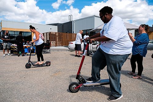 Daniel Crump / Winnipeg Free Press. Terese Bubblier (left) and Bubba B the MC (right) test out electric scooters, on demo by a company called DUNC Scooters, at the black owned businesses block party. August 29, 2020.