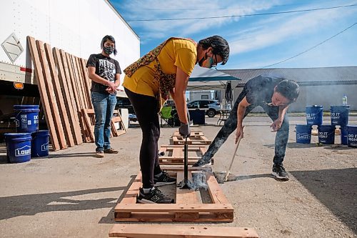 Daniel Crump / Winnipeg Free Press. Bonnie Emerson (right) instructs Debbie Ann Dedrick-Williams (middle) as she uses a hot branding iron to brand a newly made headboard. Branding is one of the final steps in the production process during the Sleep in Heavenly Peace national bed building event. The even is part of a national effort to build beds for kids in need. September 26, 2020.