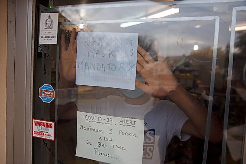 MIKE DEAL / WINNIPEG FREE PRESS
Prabjot Singh an employee at the corner store, Strikers deli and meats, on Burrows Avenue, puts a sign in the window of the store Monday morning the first day that masks need to be worn inside public spaces. The province has mandated that the Winnipeg Metropolitan Region be downgraded to the Pandemic Response System level, Restricted (Orange) for the next four weeks.
200928 - Monday, September 28, 2020.