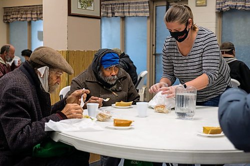 Daniel Crump / Winnipeg Free Press. Leona Schwarzhoff (right) wraps up a meal for Simon Bede (middle) as he eats a slice of pumpkin pie during Union Gospel Missions annual thanksgiving meal. October 10, 2020.