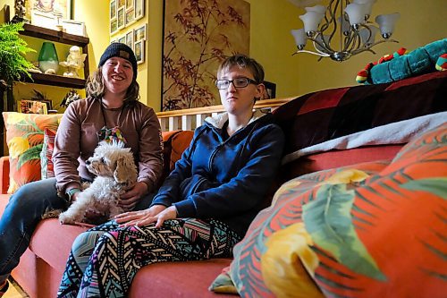 Daniel Crump / Winnipeg Free Press. (L to R) Sisters Madison and Teagan¤Zienkiewicz sit on a couch with their dog Bijou in their St. Vital home. Teagan, who has autism, isnt able to attend her day program due to safety concerns related to the coronavirus pandemic. October 22, 2020.