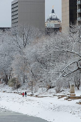 MIKE DEAL / WINNIPEG FREE PRESS
A couple walk along the snow covered riverwalk trail Wednesday morning while the Goldenboy gleams on the dome of the Manitoba Legislative building in the background.
201028 - Wednesday, October 28, 2020.