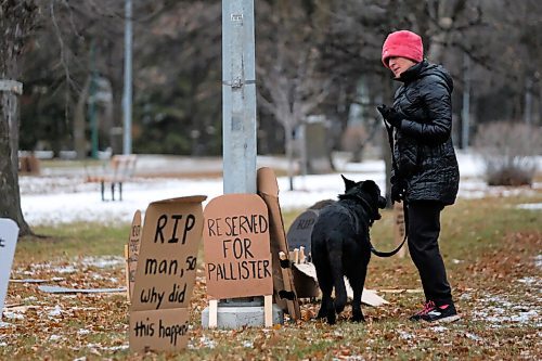 Daniel Crump / Winnipeg Free Press. Alex Ilnyckyj and her shepherd dog, Fil, stop to read cardboard tombstones setup outside Premier Brian Pallisters home on Wellington Crescent. October 31, 2020.