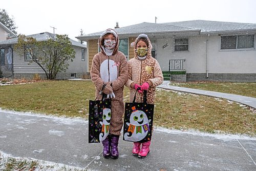 Daniel Crump / Winnipeg Free Press. (L to R) Sisters Molly Mitchell, dressed as a sloth, and Gemma Mitchell, dressed as a dear, go trick-or-treating during a specially coordinated COVID safe event on Elm Street in River Heights. October 31, 2020.
