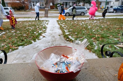 Daniel Crump / Winnipeg Free Press. A bowl of prepackaged treats sits on a door step as trick-or-treaters make their way down the sidewalk on Elm Street. October 31, 2020.
