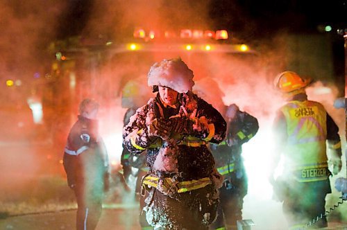 DAVID LIPNOWSKI / WINNIPEG FREE PRESS (February 25, 2011) This firefighter removes his ice covered equipment as firefighters battled a house fire at 35 Westwater Drive Friday night. Romeo Routhier is the firefighter.
