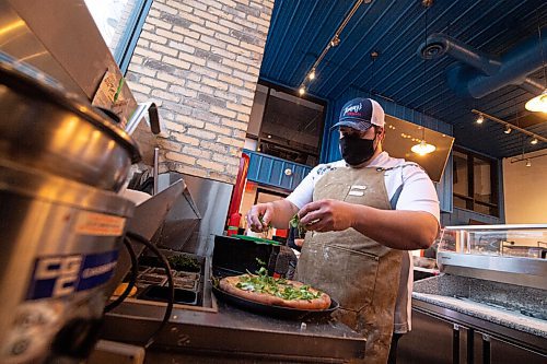 Mike Sudoma / Winnipeg Free Press
Tommys Pizzeria owner, Thomas Schenider, tops a pizza with fresh arugula Wednesday evening.
December 9, 2020