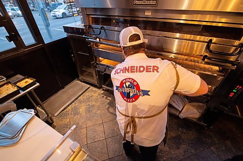 Mike Sudoma / Winnipeg Free Press
Tommys Pizzeria owner, Thomas Schenider, puts a fresh made pie into the pizza oven Wednesday evening
December 9, 2020