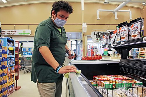 Canstar Community News Joe Carson, 25, sanitizes high-contact surfaces in Family Foods at 1881 Portage Ave. on Dec. 9. For this store supervisor, a typical shift amid code red restrictions involves rushing around to clean and make sure customers are socially distanced. /KATLYNSTREILEIN