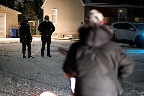 Daniel Crump / Winnipeg Free Press. Residents of Bowhill Lane, in Charleswood, stand at the end of their driveway as they listen to Dan Scramstad and Pierre Freyter sing Christmas carols. The musical duo is playing a series of curtsied concerts to help bring joy to people over the holidays. December 16, 2020.