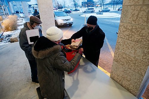 JOHN WOODS / WINNIPEG FREE PRESS
Sean Sagert, director of pastoral care at Grant Memorial Church, serves up a COVID safe drive-through meal to Florence and George Adrian who were bringing meals to their friends at the neighbouring senior building in Winnipeg Thursday, December 17, 2020. The church serves up to 450 meals.

Reporter: ?