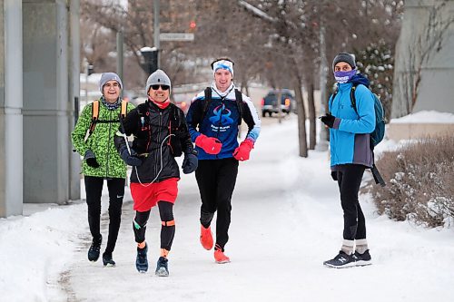 Daniel Crump / Winnipeg Free Press. Junel Malapad (red shorts) runs along Main Street  flanked by friends Jonas Eastcott (left) and Dylan Peters (right). Malapad has done a 50km run every week for a year while raising money for different charities. December 26, 2020.