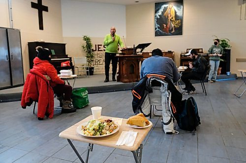 Daniel Crump / Winnipeg Free Press. A holiday meal sits on a table waiting for a guest. In the background other people eat their holiday meals while a minister preaches to them at Union Gospel Mission. January 2, 2021.