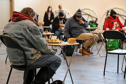 Daniel Crump / Winnipeg Free Press. People eat a holiday meal at Union Gospel Mission. Due to COVID restrictions a limited number of people are allowed in the room at a time and meals were served at individual tables spaced two meters apart. January 2, 2021.