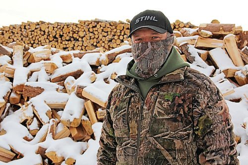 Canstar Community News Tyndall Firewood Supply owner Ernie Reimer stands in front of a pile of wood in the company lot on Dec. 19. Demand for firewood has spiked this year, he said.