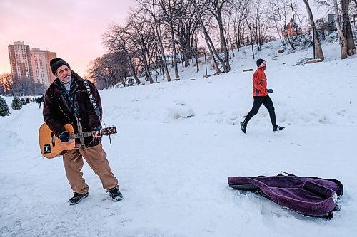 Daniel Crump / Winnipeg Free Press. Local busking icon Eric Pyle, also known to many as Eric The Great, busks on the Assiniboine river trail while a person jogs by in the background. January 23, 2021.