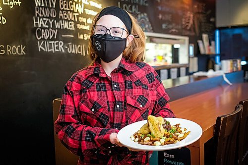 Daniel Crump / Winnipeg Free Press. Hilary Colins, kitchen manager at Le Garage, holds a plate of French Onion Poutine. The twist on a classic French- Canadian dish is Le Garages entry for Le Poutine Week. January 28, 2021.