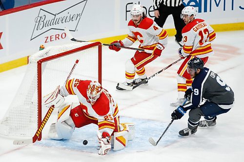 Calgary Flames goaltender Jacob Markstrom (25) goes to cover the puck as Winnipeg Jets' Andrew Copp (9) looks for his rebound as Flames Rasmus Andersson (4) and Johnny Gaudreau (13) defend during first period NHL action in Winnipeg on Thursday, February 4, 2021. THE CANADIAN PRESS/John Woods