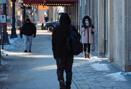 MIKE DEAL / WINNIPEG FREE PRESS
Masked pedestrians make their way along Portage Avenue during a -32C cold snap Monday morning.
210208 - Monday, February 08, 2021.