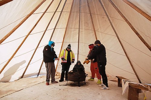 JOHN WOODS / WINNIPEG FREE PRESS
Riley Nepinak, coordinator of Anishinative, right, and volunteers take a break to warm up as they put up warming tents and teepees at Thunderbird House in Winnipeg Tuesday, February 9, 2021. 

Reporter: Abas