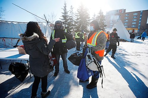 JOHN WOODS / WINNIPEG FREE PRESS
Ray, right, and a volunteer collect clothing donations from a woman at the Anishinative camp at Thunderbird House in Winnipeg Sunday, February 14, 2021.

Reporter: Sellar