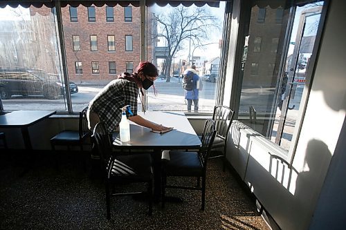 JOHN WOODS / WINNIPEG FREE PRESS
Prin Roussin, a server at The Nook restaurant in Winnipeg, cleans a table after a customer finished their meal Tuesday, February 16, 2021. Manitobas new COVID-19 restrictions allow for 25% occupancy in restaurants, but customers sitting at the same table must be from the same residence.

Reporter: Abas