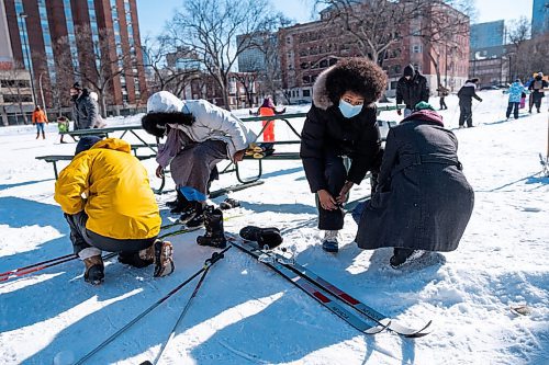 Daniel Crump / Winnipeg Free Press. Aisha Mohamed (middle left) and Abdul Mohamed (middle right) get some help putting on cross country skis as they get ready to try the sport for the first time. The skis are borrowed from the ski library which is set up at Heart in the Park at Central Park. February 20, 2021.