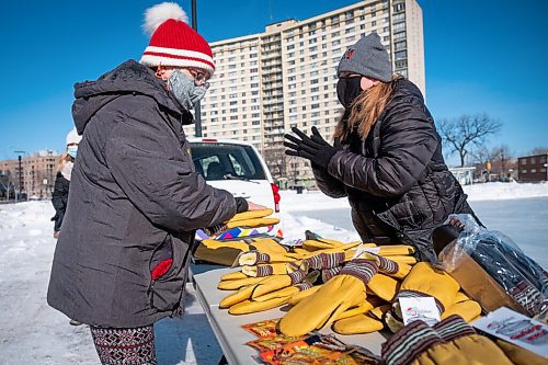 Daniel Crump / Winnipeg Free Press. Gail Anderson (left) sizes up some mitts with the help of city councillor Cindy Gilroy. The mittens, free for anyone who needs them, are being given away as part of the Heart in the Park event.  February 20, 2021.