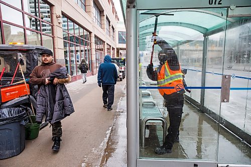 MIKE DEAL / WINNIPEG FREE PRESS
The Enviro Team with the Downtown Winnipeg BIZ cleans the bus shelter on Portage Avenue outside of the Portage Place Shopping Centre Tuesday afternoon. They were washing away blood on the benches where a 19-year-old male and a 50-year-old female were seriously assaulted Monday evening.
See Dean Pritchard story
210223 - Tuesday, February 23, 2021.