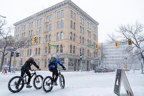 Daniel Crump / Winnipeg Free Press. Cyclists ride their fat bikes in the exchange district during heavy midday snow fall Saturday afternoon. February 27, 2021.