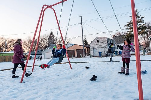 Daniel Crump / Winnipeg Free Press. Sophie Freyet-Agossa watches as three of her four children, Emmanuel Agossa (9), Marie-Rose Agossa (7), Mathéo Agossa (5) play on the swings in the park across from their St. Boniface home. February 27, 2021.