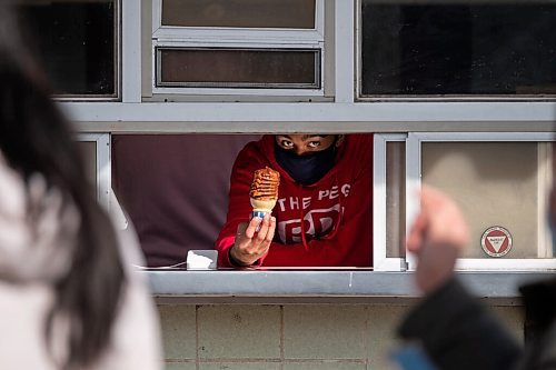 Daniel Crump / Winnipeg Free Press. An employee holds an ice cream cone at the pick-up window at the Bridge Drive-In on opening day. March 6, 2021.