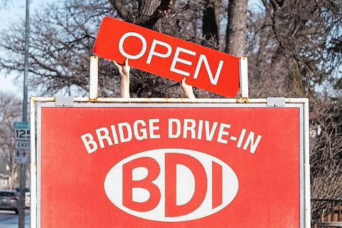 Daniel Crump / Winnipeg Free Press. An employee puts up the open sign at the Bridge Drive-In as it opens for the season. March 6, 2021.