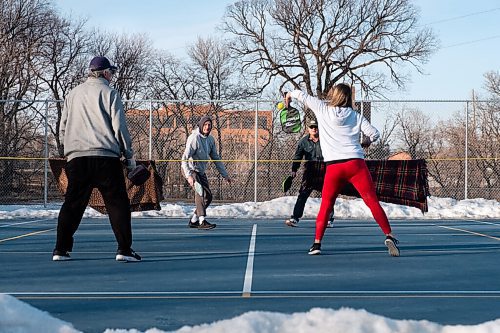 Daniel Crump / Winnipeg Free Press. Brittani Swail returns the ball as she plays pickle ball with Kliewer family on a tennis court that has been cleared of snow on a warm spring day. March 6, 2021.