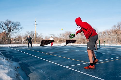 Daniel Crump / Winnipeg Free Press. Joel Kliewer serves the ball as three generations of the Kliewer family enjoy the warm spring weather as they play pickle ball on a tennis court that has been cleared of snow. March 6, 2021.