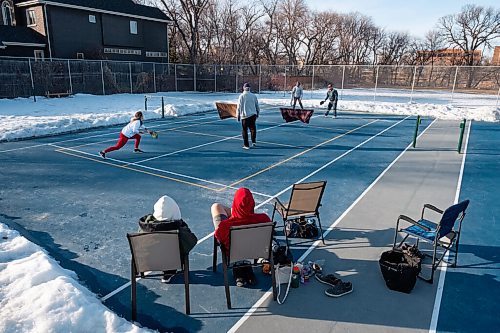 Daniel Crump / Winnipeg Free Press. Marilyn Peters Kliewer and Joel Kliewer watch on as their family members they enjoy the warm spring weather while playing pickle ball on a tennis court that has been cleared of snow. March 6, 2021.
