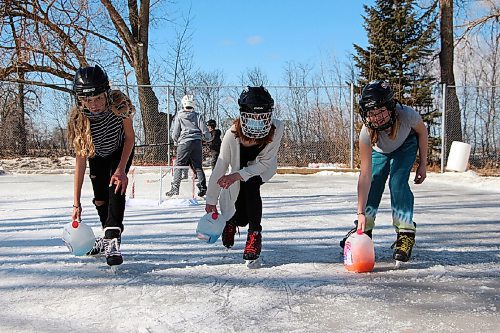 Canstar Community News From left: Students Kora Montour, Casey Moffit and Emily Holmes hold milk jug curling rocks while skating on Oakville School's ice rink during a lunch break March 2. (GABRIELLE PICHÉ/CANSTAR COMMUNITY NEWS/HEADLINER)