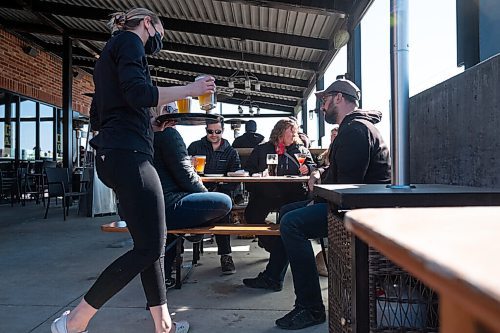Daniel Crump / Winnipeg Free Press. A server brings the Amy family as they spend time together on the patio at Fionns on Grant Avenue Saturday afternoon. March 13, 2021.