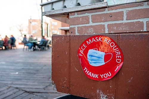 Daniel Crump / Winnipeg Free Press. A sign on the patio at Saffrons on Corydon reminds customers to wear masks. Masks are still required at restaurants unless seated at a table. March 13, 2021.