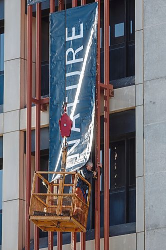 MIKE DEAL / WINNIPEG FREE PRESS
Pete Babiuk with Red River Signs attaches one of three large banners to the side of The Manitoba Museum Monday morning. 
210322 - Monday, March 22, 2021.