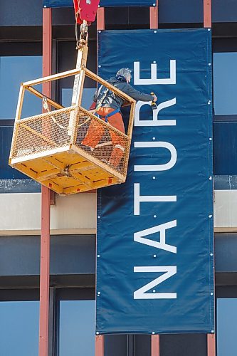 MIKE DEAL / WINNIPEG FREE PRESS
Pete Babiuk with Red River Signs attaches one of three large banners to the side of The Manitoba Museum Monday morning. 
210322 - Monday, March 22, 2021.