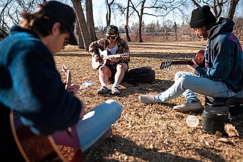 Daniel Crump / Winnipeg Free Press. Bryan Nieva (Pearl Harbour hat), Noah Monney (black toque) and Stephen Adamopoulos (black hat) jam in St. Vital Park Friday evening. The three friends began jamming together as a way to combat pandemic isolation and have titled their band Well Talk Later. April 2, 2021.