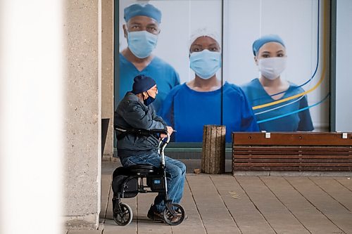 Daniel Crump / Winnipeg Free Press. A person sits and smokes outside as they wait to get their COVID-19 vaccination at the RBC Convention Centre. April 3, 2021.