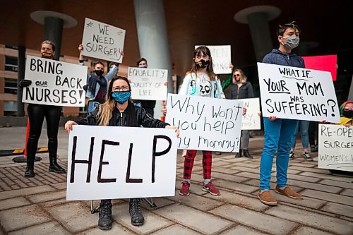 Daniel Crump / Winnipeg Free Press. Sara Corrigan (seated) and daughter Aubrey (middle right) take part in a rally in front of the HSC Womens Hospital to draw attention to cancelled surgeries and other issues that have resulted in women not getting health care they need during the pandemic. April 3, 2021.