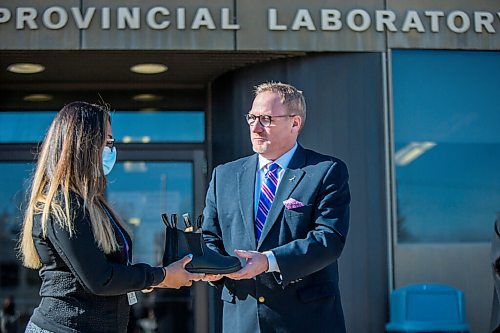 MIKAELA MACKENZIE / WINNIPEG FREE PRESS

Finance minister Scott Fielding hands laboratory technician Chaturika Jayawardanamake a pair of shoes at a budget announcement at Cadham Provincial Laboratory in Winnipeg on Tuesday, April 6, 2021. For Carol Sanders story.

Winnipeg Free Press 2021