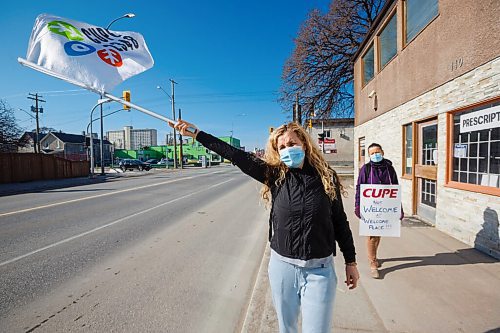 MIKE DEAL / WINNIPEG FREE PRESS
Welcome Place employees, Valentina Cerka (left) and Flora Aruna (right) walk along Isabel Street with flags and placards after being locked out of work at Welcome Place Tuesday morning.
Valentina has been working at Welcome Place for the last 22 years, while Flora has been at Welcome Place for 19 years.
Employee's of Welcome Place came to work Tuesday morning to find the doors were locked. Their union representative, Scott Clark, was on hand to start a picket line as soon as the lockout started.
210427 - Tuesday, April 27, 2021.